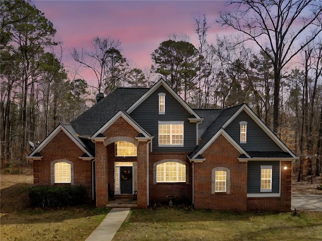 view of front of home with brick siding and a lawn