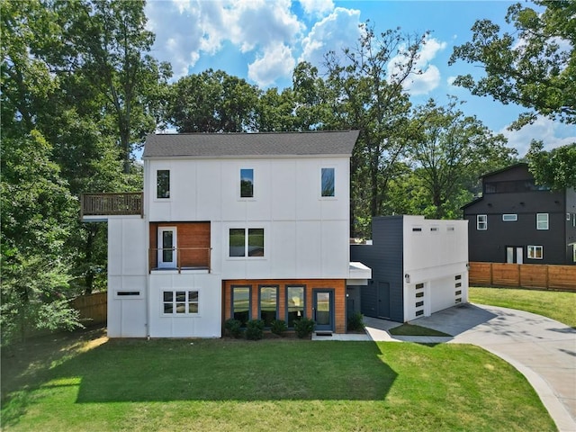 contemporary house featuring a balcony, fence, concrete driveway, a front lawn, and board and batten siding