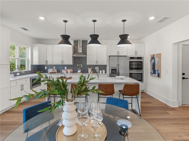 kitchen with wall chimney exhaust hood, appliances with stainless steel finishes, light countertops, and decorative backsplash