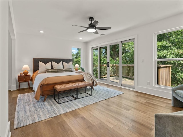 bedroom with access to outside, multiple windows, wood finished floors, and recessed lighting