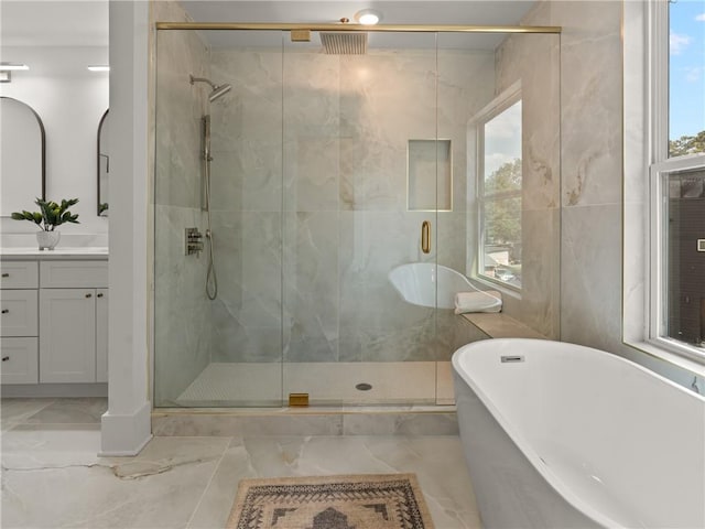 full bathroom featuring a stall shower, marble finish floor, a freestanding tub, and vanity