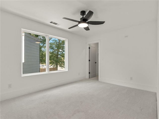 empty room with carpet floors, ceiling fan, visible vents, and baseboards