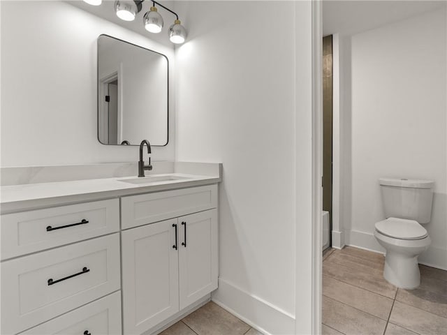 bathroom featuring toilet, vanity, tile patterned flooring, baseboards, and walk in shower