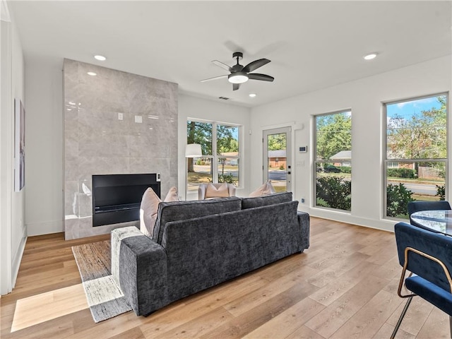 living area featuring light wood finished floors, ceiling fan, a tile fireplace, and recessed lighting