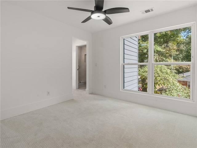 unfurnished room with carpet floors, a wealth of natural light, visible vents, and a ceiling fan