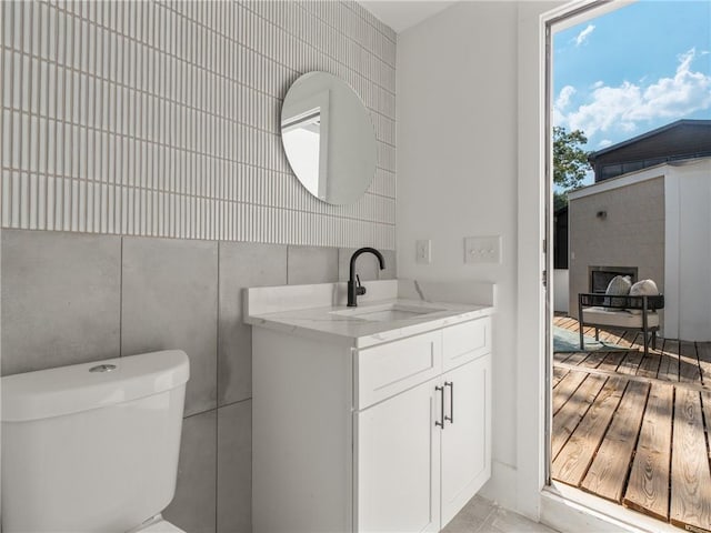 bathroom with tile walls, vanity, and toilet