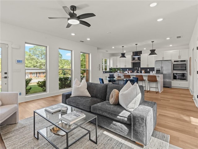 living area with ceiling fan, light wood finished floors, visible vents, and recessed lighting