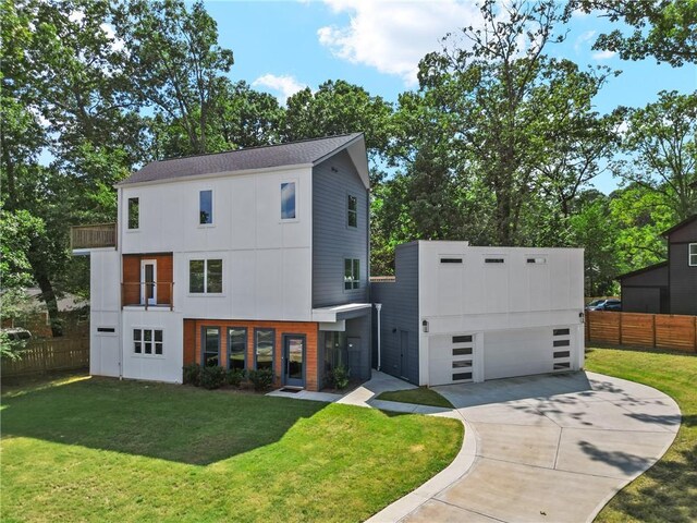 contemporary house with concrete driveway, an attached garage, fence, board and batten siding, and a front yard