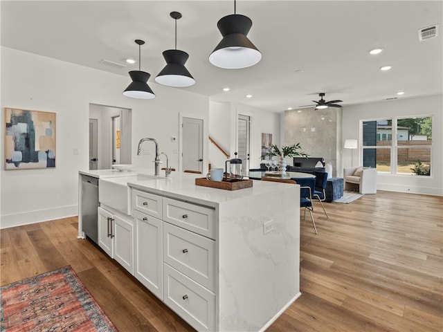 kitchen featuring stainless steel dishwasher, light wood-type flooring, a sink, and visible vents