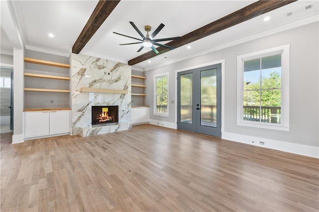 unfurnished living room with built in shelves, crown molding, a high end fireplace, and light hardwood / wood-style floors