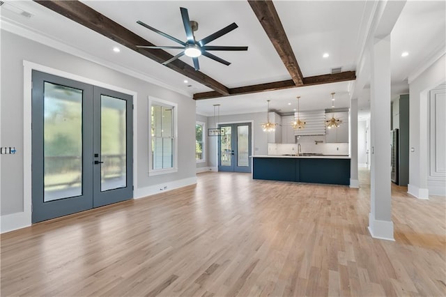 unfurnished living room featuring ceiling fan, french doors, sink, beamed ceiling, and light wood-type flooring