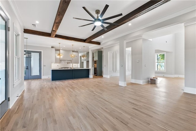 unfurnished living room featuring ceiling fan with notable chandelier, beam ceiling, and light wood-type flooring