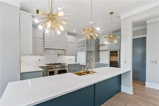 kitchen featuring double oven range, backsplash, an inviting chandelier, gray cabinets, and beverage cooler