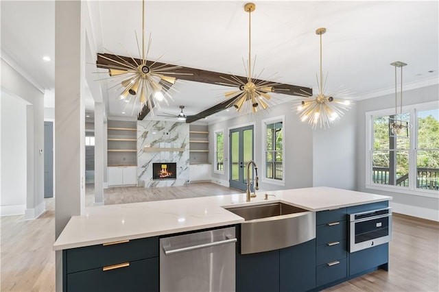 kitchen with stainless steel dishwasher, ornamental molding, sink, decorative light fixtures, and a premium fireplace