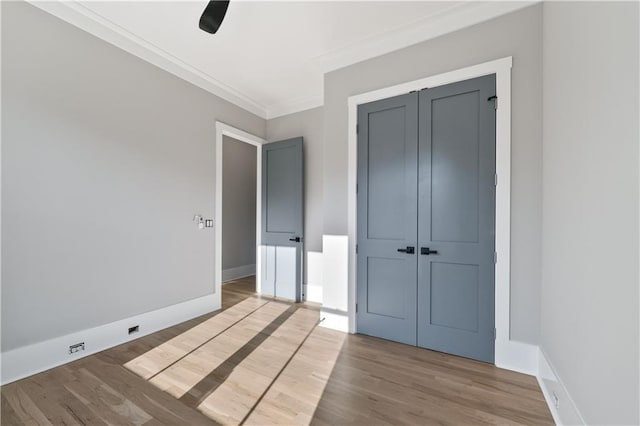 unfurnished bedroom with ceiling fan, a closet, crown molding, and hardwood / wood-style flooring