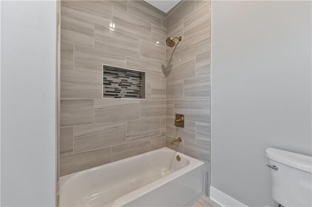 bathroom featuring toilet and tiled shower / bath