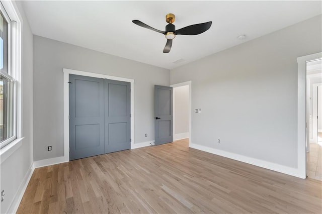 unfurnished bedroom featuring ceiling fan, a closet, and light wood-type flooring