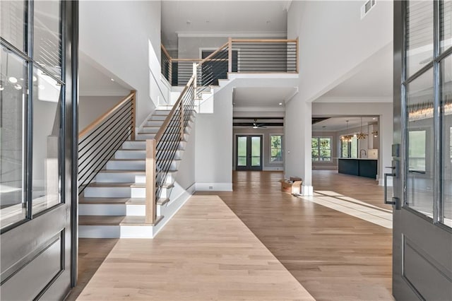 foyer featuring crown molding, french doors, hardwood / wood-style floors, and ceiling fan with notable chandelier