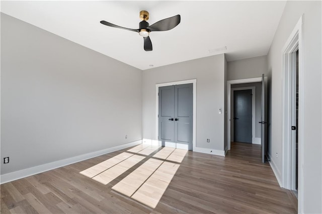 unfurnished bedroom with ceiling fan, a closet, and hardwood / wood-style floors