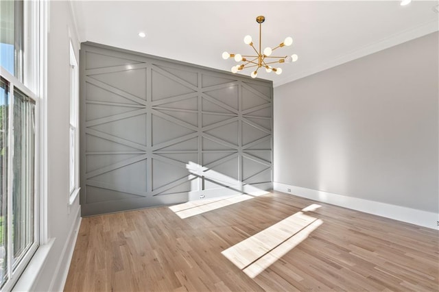 empty room with ornamental molding, a chandelier, and light wood-type flooring