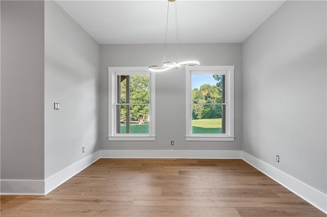 unfurnished dining area featuring an inviting chandelier and light wood-type flooring