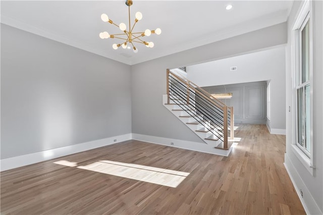 spare room with light hardwood / wood-style floors, ornamental molding, and an inviting chandelier