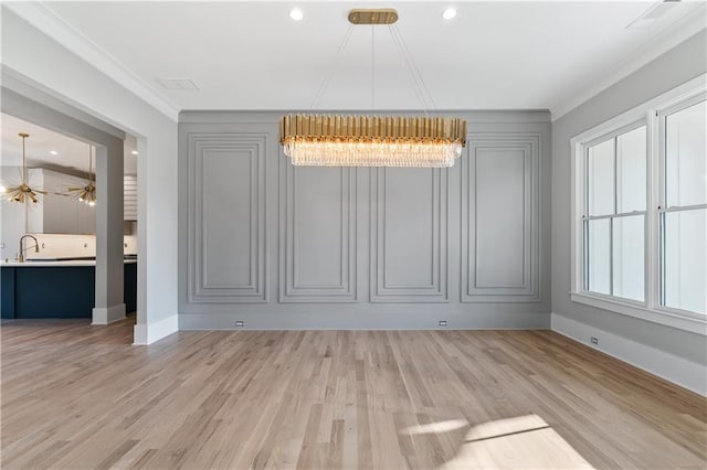 unfurnished dining area with light hardwood / wood-style flooring, crown molding, and a notable chandelier