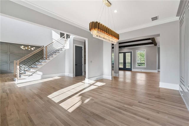 unfurnished living room featuring hardwood / wood-style flooring, french doors, crown molding, and an inviting chandelier