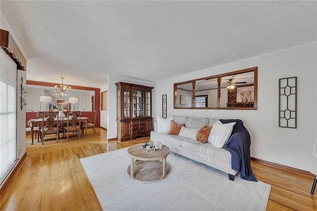 living room featuring ceiling fan with notable chandelier and light hardwood / wood-style floors