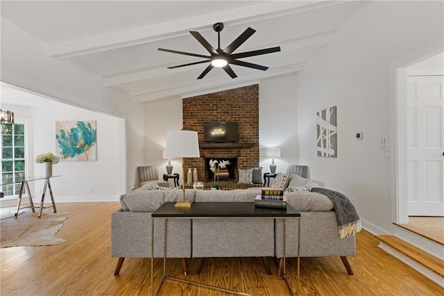 living room featuring wood-type flooring, a brick fireplace, lofted ceiling with beams, and ceiling fan