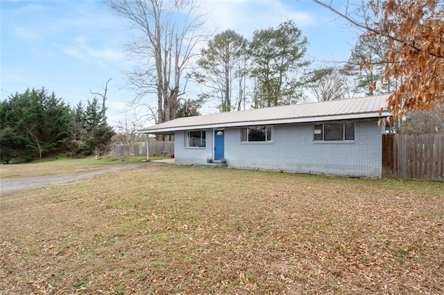 view of front facade with metal roof, a front lawn, fence, and brick siding