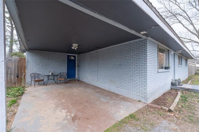 exterior space featuring fence, an attached carport, a patio, and brick siding