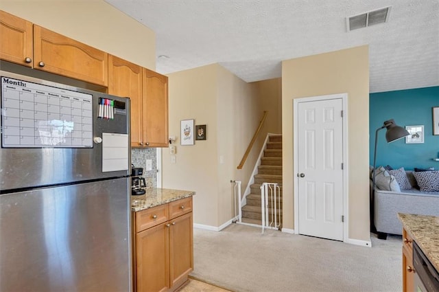 kitchen with light stone countertops, stainless steel fridge, light carpet, and tasteful backsplash