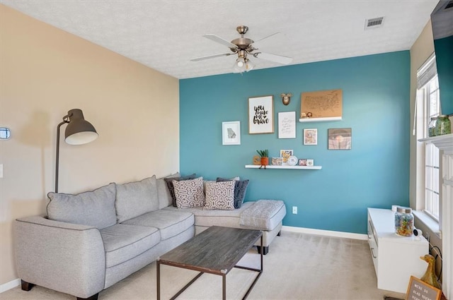 carpeted living room featuring ceiling fan and a textured ceiling