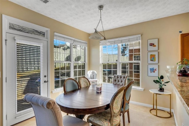 carpeted dining room featuring a textured ceiling