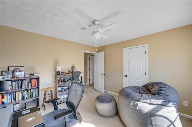 carpeted office space with a textured ceiling and ceiling fan