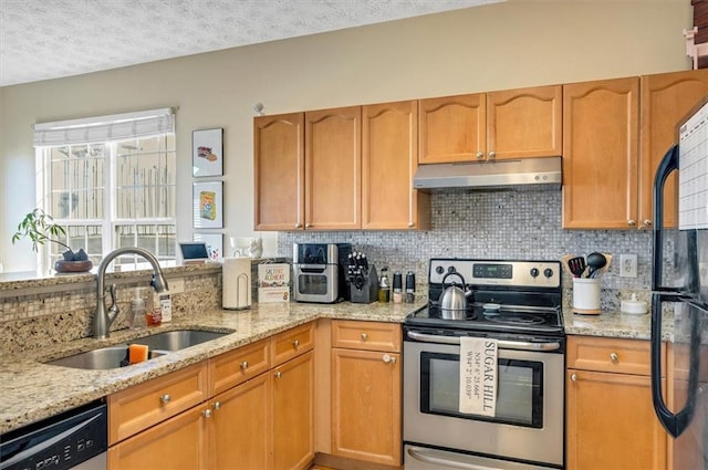 kitchen with light stone countertops, a textured ceiling, appliances with stainless steel finishes, decorative backsplash, and sink