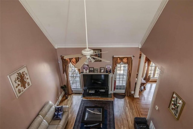 living area with a ceiling fan, crown molding, baseboards, and wood finished floors