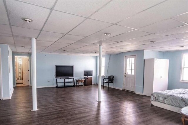 basement with dark hardwood / wood-style flooring, plenty of natural light, and a drop ceiling