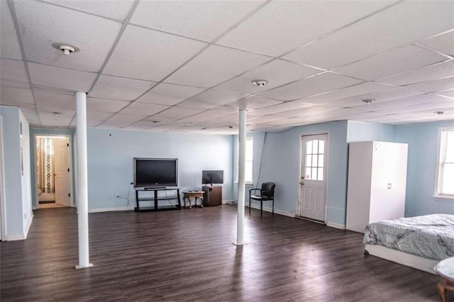 basement with wood finished floors, a paneled ceiling, and baseboards