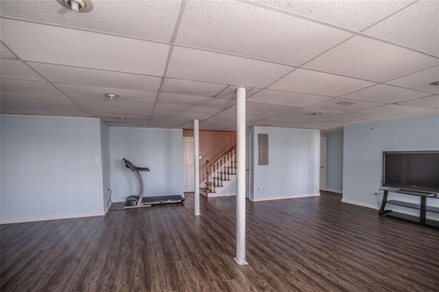 finished basement with a paneled ceiling, baseboards, stairway, and dark wood finished floors