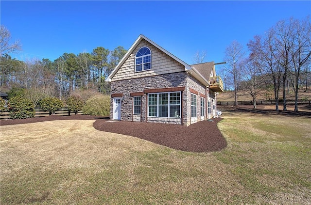 view of property exterior with stone siding, a yard, and fence