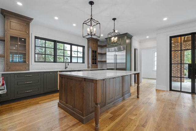 kitchen featuring built in refrigerator, light wood-style flooring, a kitchen island, and open shelves