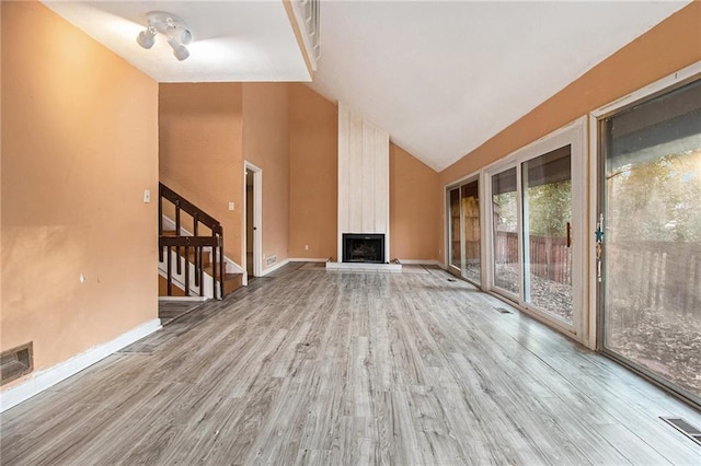 unfurnished living room featuring vaulted ceiling, a fireplace, and light hardwood / wood-style floors