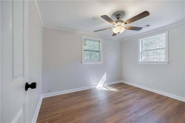 spare room featuring crown molding, baseboards, ceiling fan, and wood finished floors