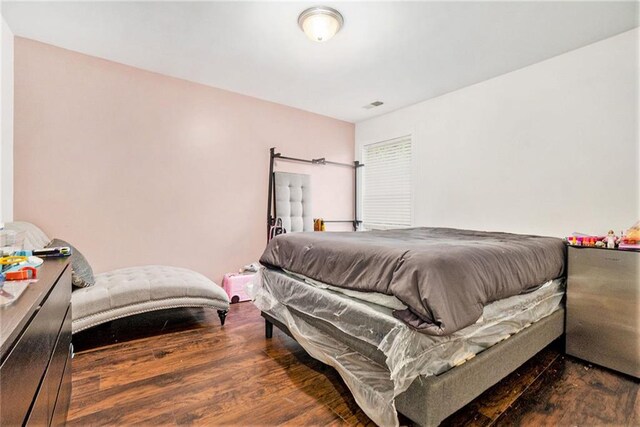 bedroom featuring visible vents, wood finished floors, and stainless steel fridge