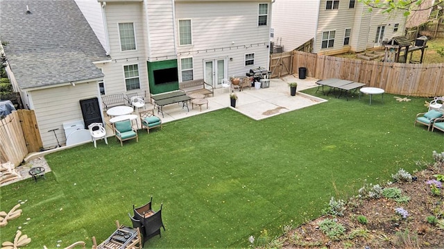 back of property with a fenced backyard, roof with shingles, and a yard