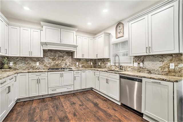 kitchen featuring decorative backsplash, appliances with stainless steel finishes, a sink, custom range hood, and dark wood-type flooring