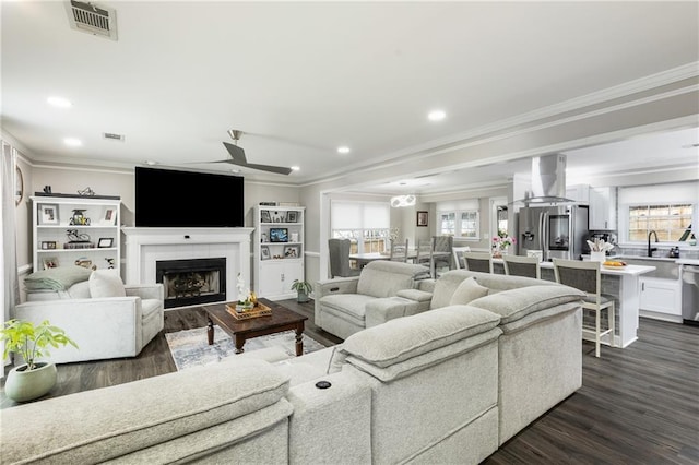 living room with recessed lighting, a fireplace, visible vents, dark wood finished floors, and crown molding