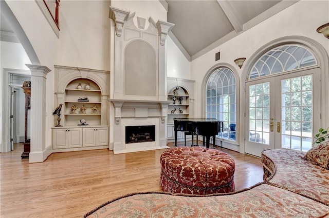 8455 Abingdon Ln, Duluth, GA 30097 - living room featuring high vaulted ceiling, light wood finished floors, built in features, french doors, and a high end fireplace